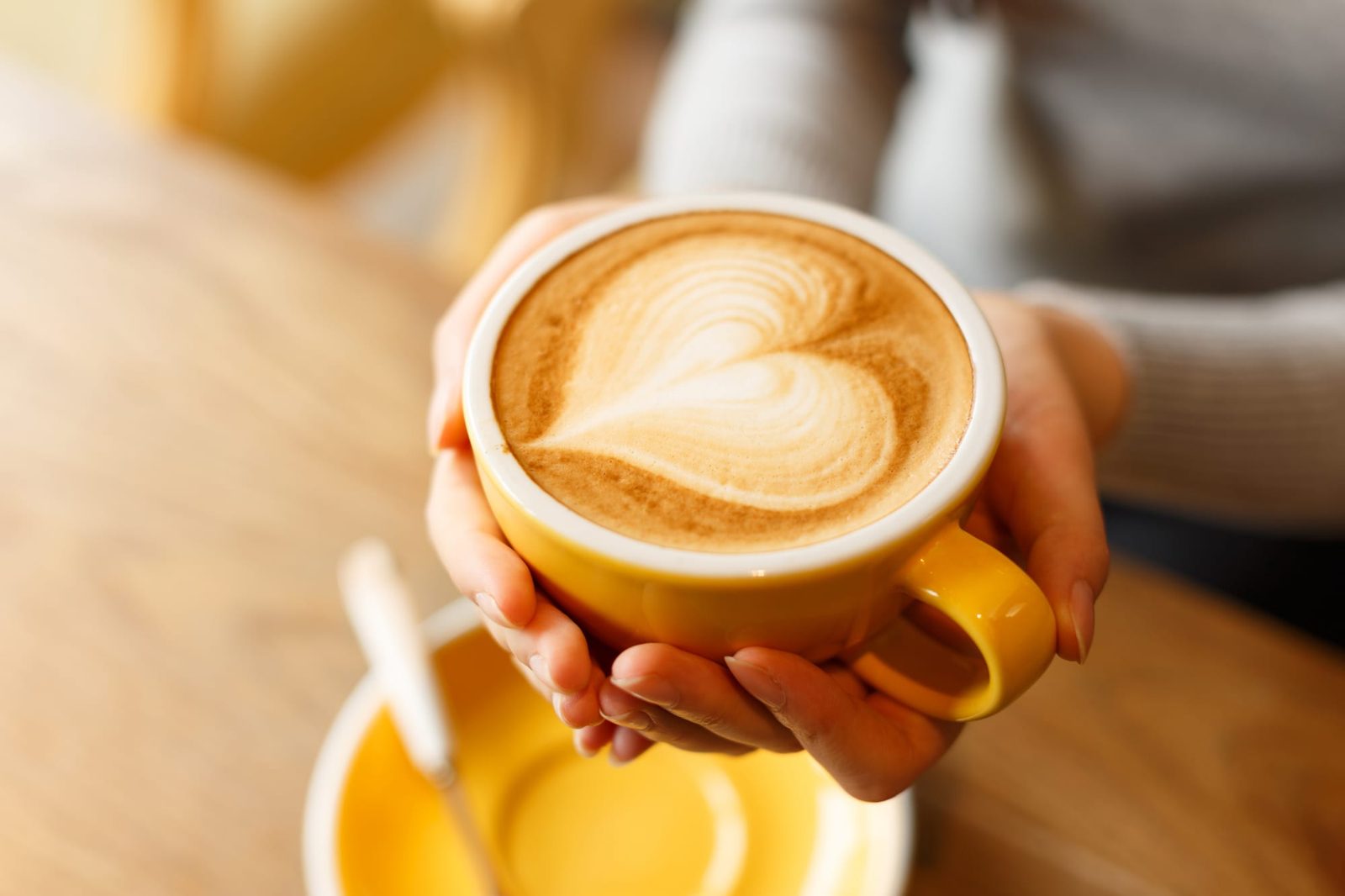 A latte with latte art held in both hands